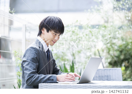 カフェのテラス席で仕事をする若い男性 カフェのテラス席で仕事をする若い男性 142741132