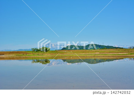 初夏田植え前の田んぼに映る残雪の越後三山山並み 142742032