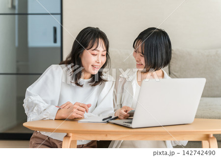 パソコンでネットショッピングを楽しむ母親と娘。商品や口コミを一緒に見る仲良し親子 パソコンでネットショッピングを楽しむ母親と娘。商品や口コミを一緒に見る仲良し親子 142742490