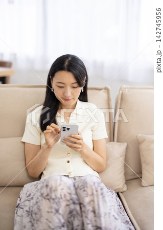 ソファでスマートフォンを操作する若い日本人女性 142745956