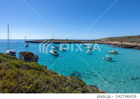 Multiple sailboats and motorboats moored in stunning crystal clear turquoise waters of secluded Cala Varques bay on a sunny summer day in Mallorca, Balearic Islands Multiple sailboats and motorboats moored in stunning crystal clear turquoise waters of secluded Cala Varques bay on a sunny summer day in Mallorca, Balearic Islands 142746416