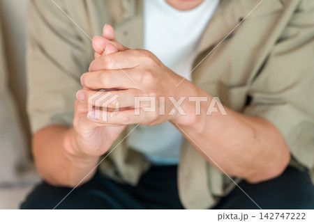手の痛みや違和感に悩み手首を押さえる男性。関節痛や腱鞘炎をイメージした健康素材 手の痛みや違和感に悩み手首を押さえる男性。関節痛や腱鞘炎をイメージした健康素材 142747222