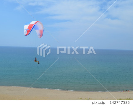 海辺の上空を滑空するパラグライダーの爽やかな風景 142747586