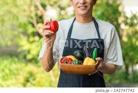 収穫した新鮮な夏野菜を手に笑顔を見せる男性。農家と産地直送、ふるさと納税のイメージ 収穫した新鮮な夏野菜を手に笑顔を見せる男性。農家と産地直送、ふるさと納税のイメージ 142747742