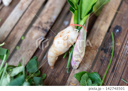 Fresh galangal root lemongrass bundled green aromatic leaves rustic wood representing traditional Thai cooking ingredients natural Asian herbs 142748501
