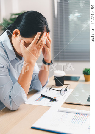 Stressed businesswoman covering her face while working on a laptop in a modern office, showing burnout, anxiety, fatigue, work pressure, deadline stress, and workplace mental health. Stressed businesswoman covering her face while working on a laptop in a modern office, showing burnout, anxiety, fatigue, work pressure, deadline stress, and workplace mental health. 142749194