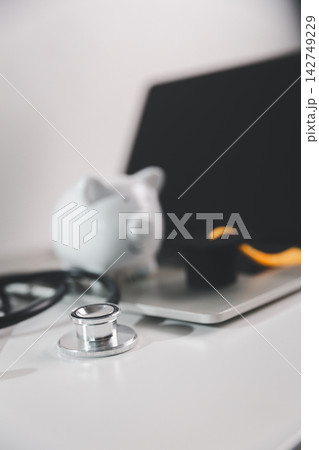 Stethoscope with laptop, piggy bank and graduation cap, representing online medical education, digital healthcare learning, tuition planning and financial preparation for healthcare careers. Stethoscope with laptop, piggy bank and graduation cap, representing online medical education, digital healthcare learning, tuition planning and financial preparation for healthcare careers. 142749229