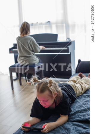 Cheerful young child girl playing using pc tablet gadget. Kids spending time at home Cheerful young child girl playing using pc tablet gadget. Kids spending time at home 142750650