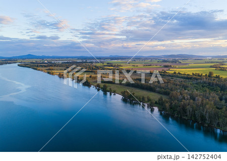 Aerial view over the expansive Clarence River and surrounding farmland near Yamba, showing the broad waterway winding through the rural landscape beneath a softly clouded sky  142752404