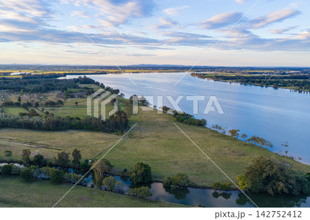Aerial view of Romiaka Channel and the Clarence River winding through farmland on Palmers Island near Yamba, with cultivated fields, rural vegetation and waterways extending across the landscape  142752412