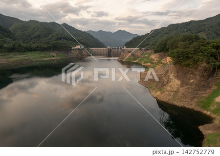 夕暮れ時の湖面に空と雲が映り込む八ッ場ダム堤体とダム湖の景観 142752779