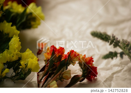 Bright yellow and orange dried statice flowers on crumpled craft paper Bright yellow and orange dried statice flowers on crumpled craft paper 142752828