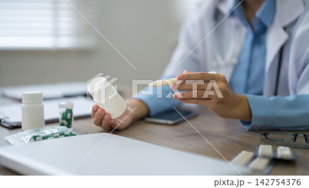 Doctor explaining medication bottle and prescription to patient during consultation in clinic with copy space Doctor explaining medication bottle and prescription to patient during consultation in clinic with copy space 142754376