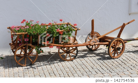 Wooden cart filled with blooming pink flowers 142754536