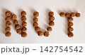 Walnuts arranged to spell "NUT" on a plain white surface 142754542