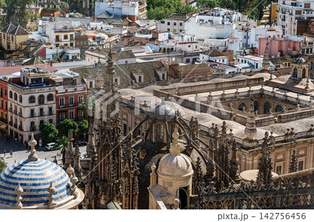 Aerial view of Seville rooftops with gothic cathedral spires and blue tiled domes Aerial view of Seville rooftops with gothic cathedral spires and blue tiled domes 142756456