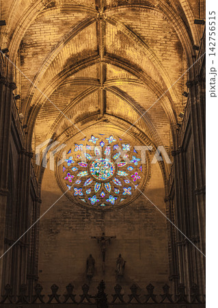 Stained glass rose window glowing above the crucifix in Seville Cathedral's Gothic nave Stained glass rose window glowing above the crucifix in Seville Cathedral's Gothic nave 142756515