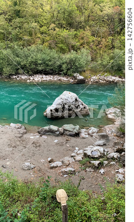Large grey boulder resting in a vibrant turquoise mountain stream flowing through a dense forest Large grey boulder resting in a vibrant turquoise mountain stream flowing through a dense forest 142756604