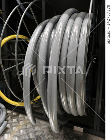 Gray hose wound into a neat coil is available on retail shelves in a construction supply department Gray hose wound into a neat coil is available on retail shelves in a construction supply department 142757379
