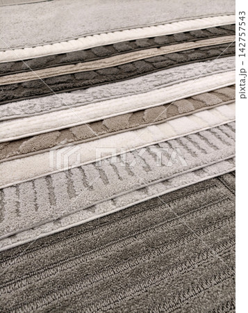 Rug collection displayed in stacked piles with elegant textures and colorful woven designs 142757543