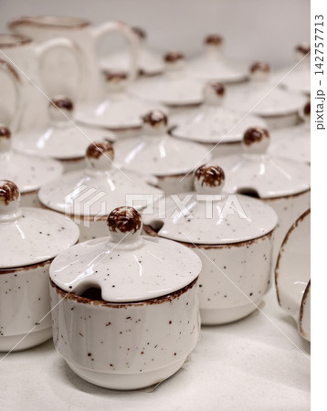 Ceramic sauce bowls or sugar containers in light tones lined up in retail display highlighting simple tableware collection intended for serving and storage in modern kitchen settings 142757713
