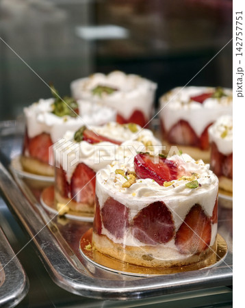 Pastries with white cream and fresh strawberry slices displayed in a pastry shop showcase, presenting an attractive sweet dessert with a delicate creamy texture and fruit topping Pastries with white cream and fresh strawberry slices displayed in a pastry shop showcase, presenting an attractive sweet dessert with a delicate creamy texture and fruit topping 142757751