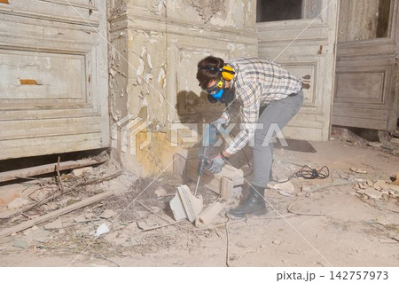 Manual laborer utilizes pneumatic tool for surface destruction purposes Manual laborer utilizes pneumatic tool for surface destruction purposes 142757973