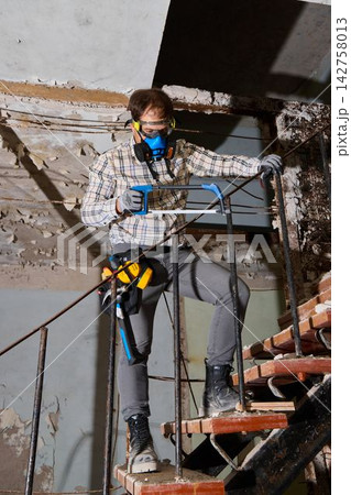 Construction professional carefully dismantles urban staircase structure 142758013