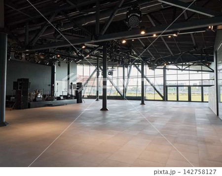Indoor concert hall with exposed steel trusses stage lighting rigs panoramic windows overlooking city skyline during daylight showcasing modern industrial auditorium interior mounted equipment Indoor concert hall with exposed steel trusses stage lighting rigs panoramic windows overlooking city skyline during daylight showcasing modern industrial auditorium interior mounted equipment 142758127