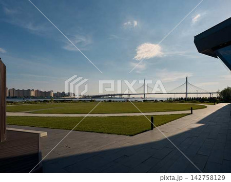 City skyline on riverfront with cable-stayed bridge, bright daylight, calm water reflections, and modern waterfront park City skyline on riverfront with cable-stayed bridge, bright daylight, calm water reflections, and modern waterfront park 142758129