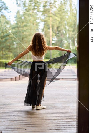 Serene woman displays open scarf overlooking tranquil lakeside view Serene woman displays open scarf overlooking tranquil lakeside view 142758284