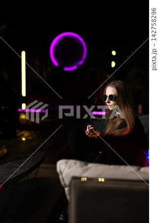 Woman relaxing at bar with luminous drink and reflective feelings Woman relaxing at bar with luminous drink and reflective feelings 142758296