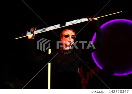 Lively entertainer showcasing colorful lighting and dynamic stance 142758347