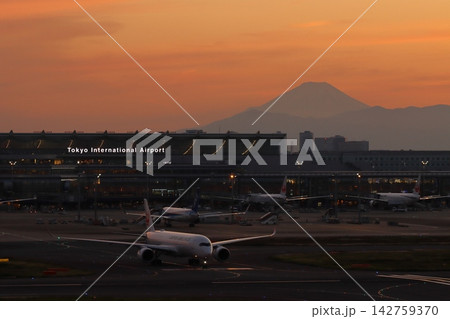 夕焼けのシルエットで浮かび上がる富士山を背景にした羽田空港の夜景 142759370