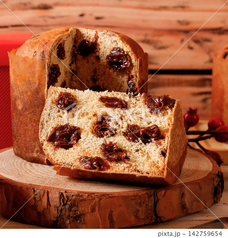 Sliced Christmas panettone with creamy chocolate filling on a rustic wooden table during a Christmas celebration. 142759654