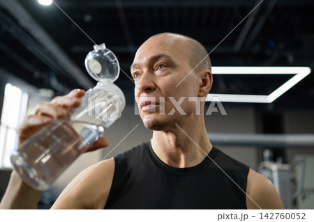 Athletic man drinking water after gym workout Athletic man drinking water after gym workout 142760052