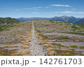 秋晴れの空の下で遥かな山並みへと一本の登山道が伸びる高山帯の稜線 142761703