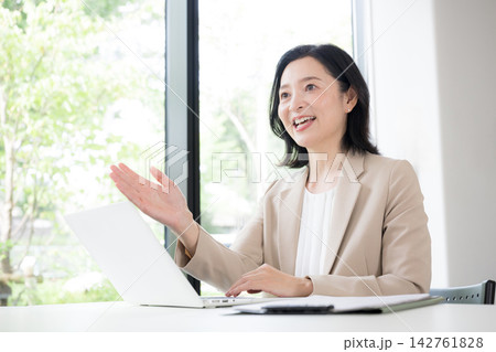 笑顔で顧客と対面相談する50代女性、オフィスで説明や提案を行うビジネスウーマン　コミュニケーション 142761828