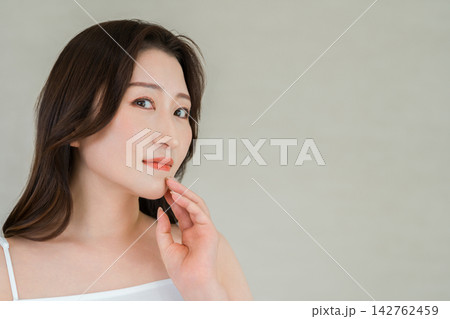 フェイスラインに手を添える40代50代女性。エイジングケアと美肌の美容イメージ フェイスラインに手を添える40代50代女性。エイジングケアと美肌の美容イメージ 142762459