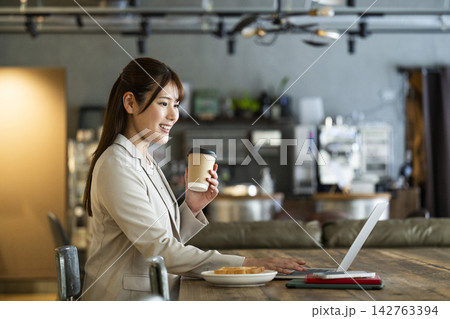 カフェで朝食を食べながら仕事をする若い女性 142763394