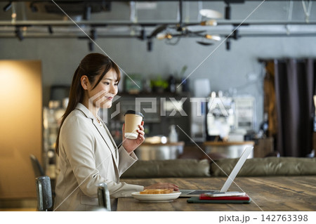 カフェで朝食を食べながら仕事をする若い女性 142763398