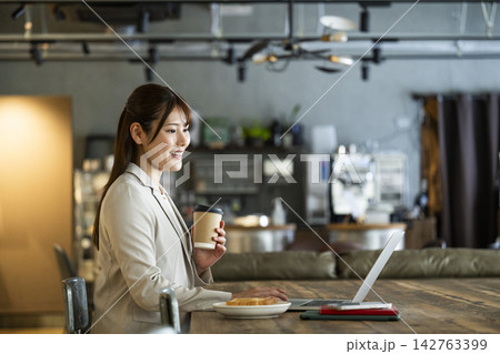 カフェで朝食を食べながら仕事をする若い女性 142763399
