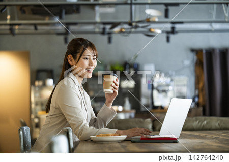 カフェで朝食を食べながら仕事をする若い女性 カフェで朝食を食べながら仕事をする若い女性 142764240