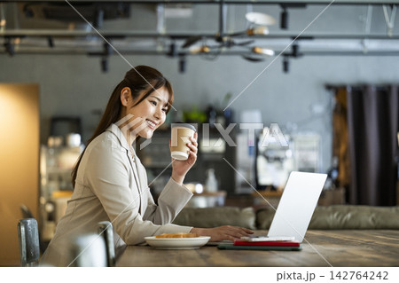 カフェで朝食を食べながら仕事をする若い女性 142764242