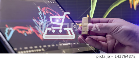 Online gold purchasing concept. Hand holding a gold bar with glowing shopping cart icon and financial trading charts Online gold purchasing concept. Hand holding a gold bar with glowing shopping cart icon and financial trading charts 142764878