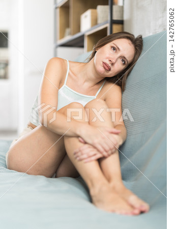 Sad adult woman sitting on sofa in living room 142765062