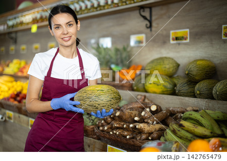 Girl selling food at a supermarket offers to buy juicy melon 142765479