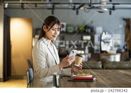 カフェで朝食を食べながらスマホを見る若い女性 142766142