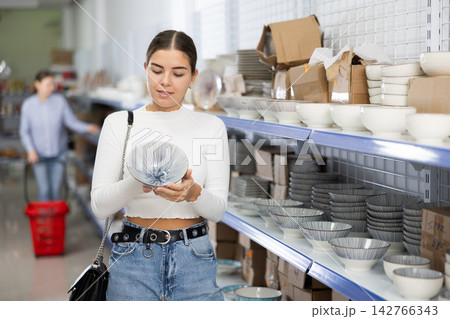 Young woman in supermarket is choosing plates with Asian pattern 142766343
