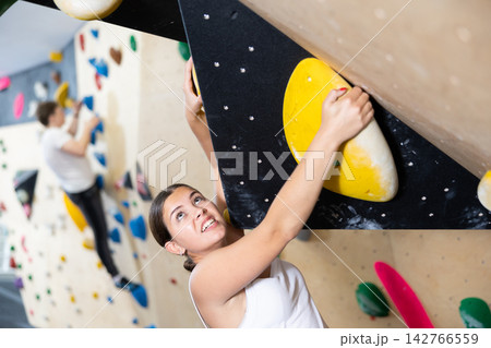 Young woman practicing rock climbing on climbing wall 142766559